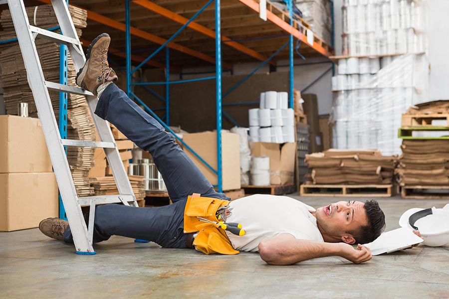 Falling from height accident claim, side view of male worker lying on the floor in warehouse